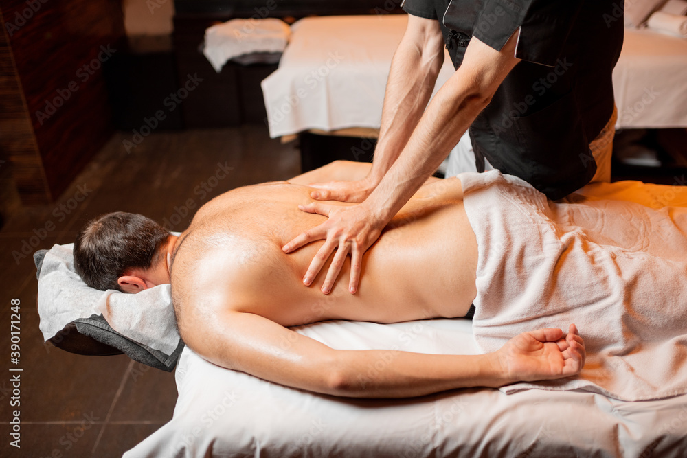 Fototapeta premium Man receiving a deep massage on his back from professional therapist at luxury spa salon