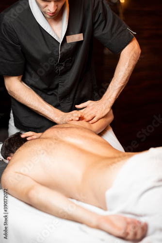 Professional masseur doing a deep massage to a male client at Spa salon  shoulder massage