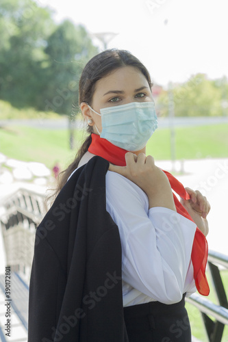 Vertical shot of a Caucasian woman wearing a sanitary mask outdoors-concept of the new normal photo