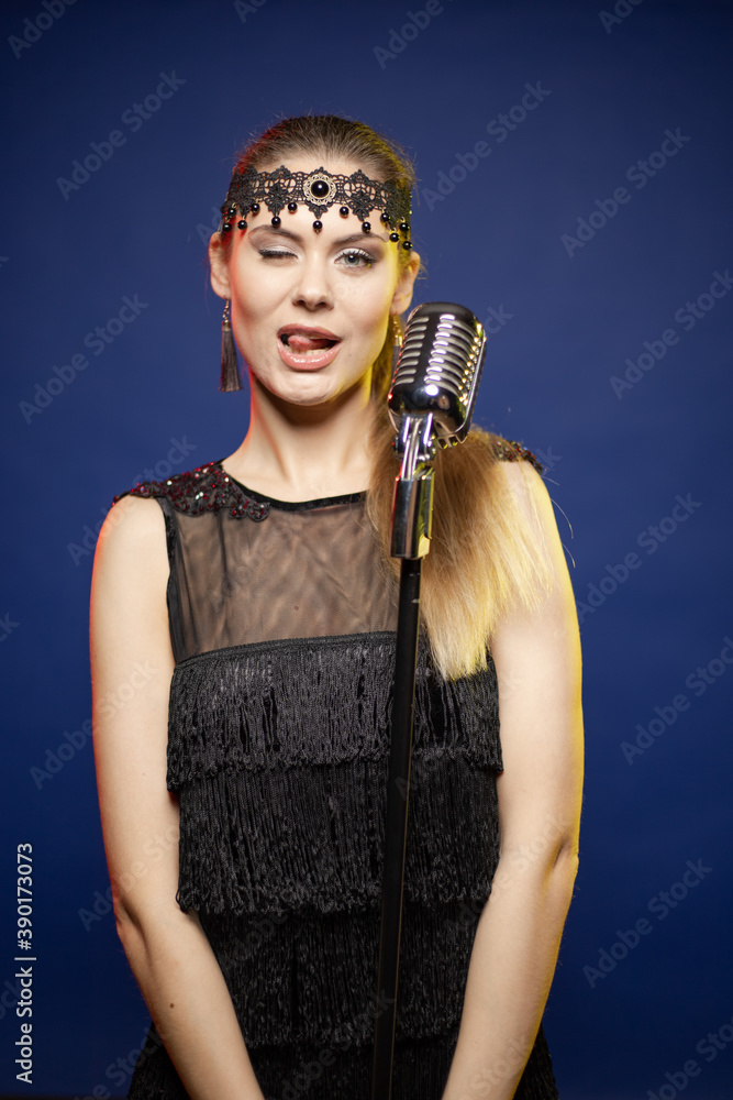 Young woman with long hair in a black dress in a retro style on a blue