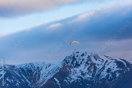 Paragliding against snow-capped Andes mountains during winter season in Esquel, Patagonia, Argentina