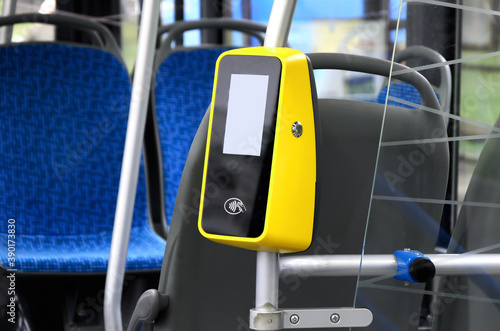 Vertical handrail with bus payment terminal in passenger compartment. Terminal for contactless payment of fare for ground public transport. Selective focus