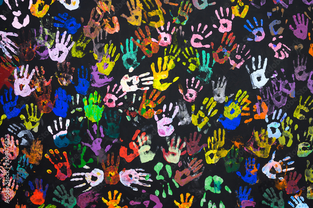 Many multi-colored prints of human hands on a black background. Peace and friendship concept. Focusing on the center of the frame. Many multi-colored prints of human hands on a black background. Peace and friendship concept. Focusing on the center of the frame.