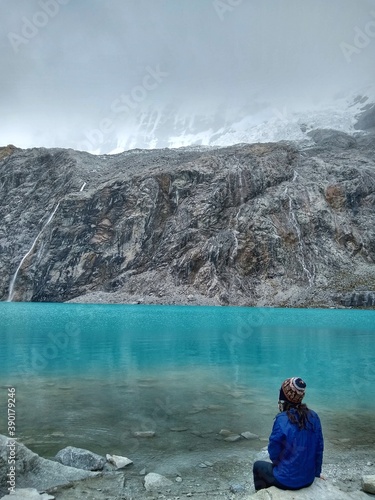 Fototapeta Naklejka Na Ścianę i Meble -  Girl at Laguna Paron, Huaraz, Peru. A blue-green lake in the Cordillera Blanca on the Peruvian Andes. At 4185 meters above sea level, it's surrounded by snowy peaks and a pyramid mountain. 