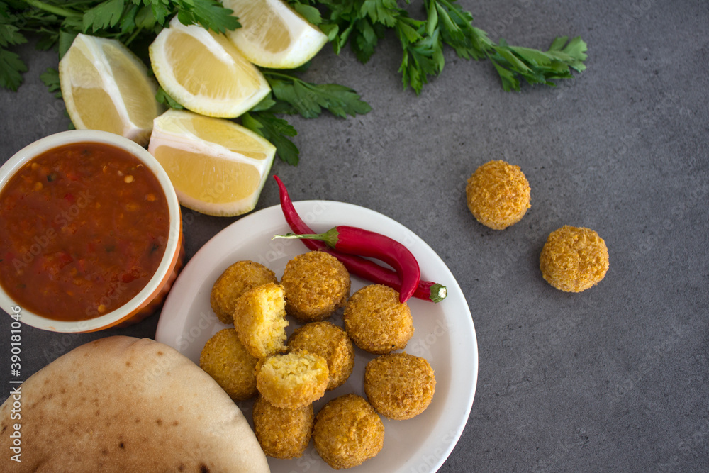 Fresh made falafels on dark grey table with lemon slices, chili pepper and parsley. Authentic food of Israel. Ingredients top view photo. Healthy eating concept. 
