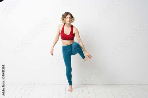 A woman in full growth In a bright room yoga meditation is engaged in sports
