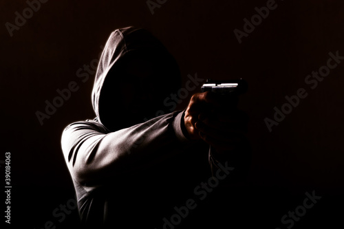 Obraz na plátně dangerous hooded man threatens with a pistol shot in his hands