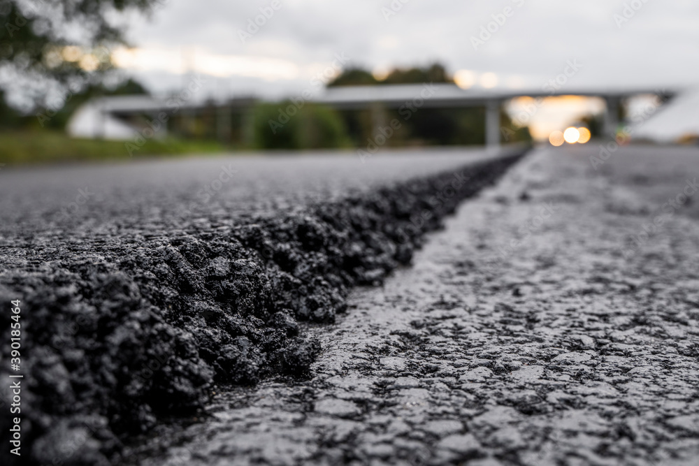 A large layer of fresh hot asphalt. Layer of asphalt raw material in a shallow depth of field. Rollers rollin fresh hot asphalt on the new road. Road construction. Construction of a new road. A large layer of fresh hot asphalt. Layer of asphalt raw material in a shallow depth of field. Rollers rollin fresh hot asphalt on the new road. Road construction. Construction of a new road.