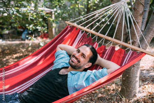 Young man is resting in a hammock in the garden