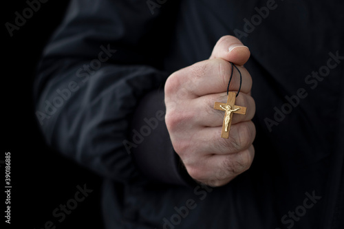 Foto Wooden crucifix in male hand on black background.