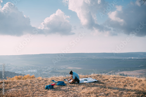 Young male tourist puts a tent in the mountains. © Anna