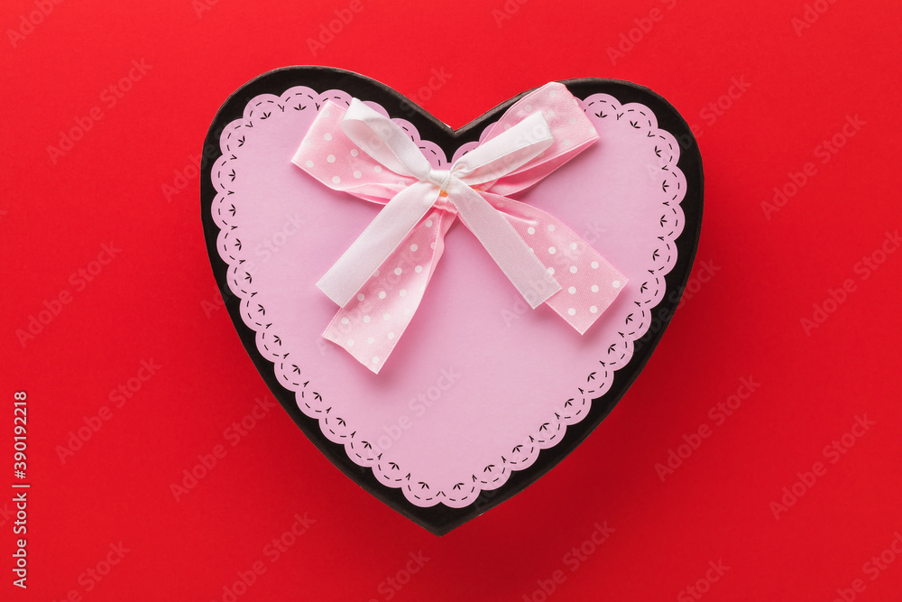 Gift box with a bow in the shape of a heart on a red background, top view Gift box with a bow in the shape of a heart on a red background, top view