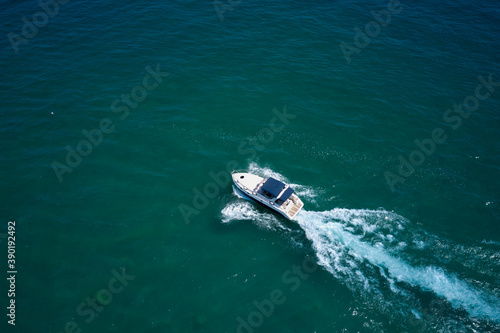 Drone view of a boat sailing. Top view of a white boat sailing to the blue sea. Motor boat in the sea. Travel - image. © Berg