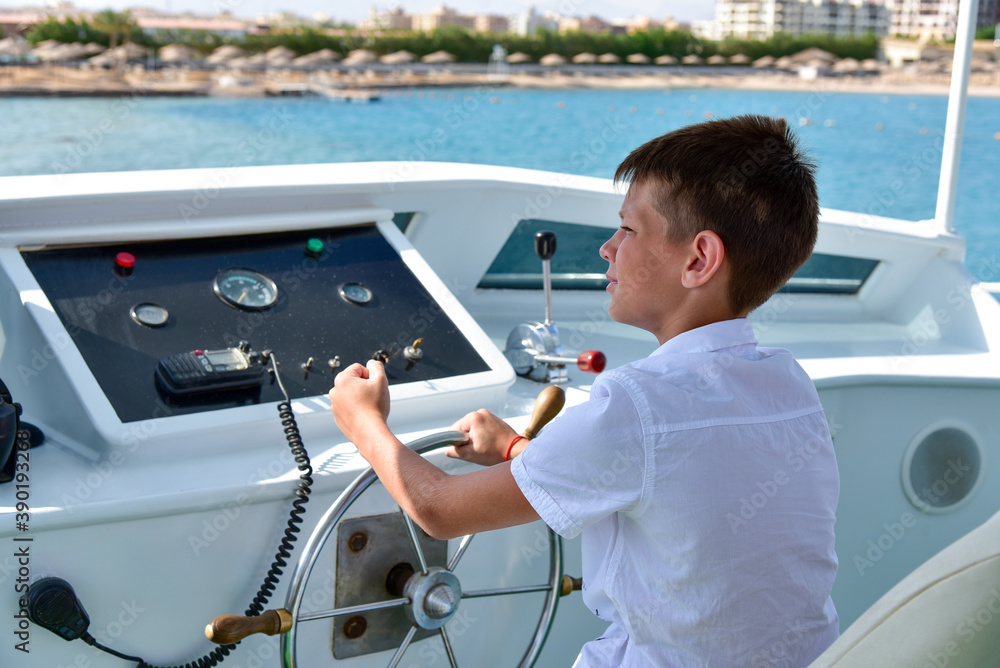 Obraz premium Teen at the helm controls a yacht at sea