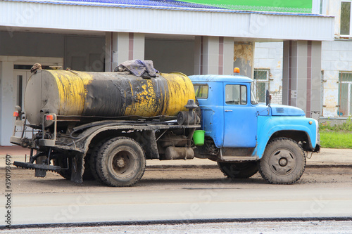 A truck with a blue cab with a yellow tank to transport molten bitumen.