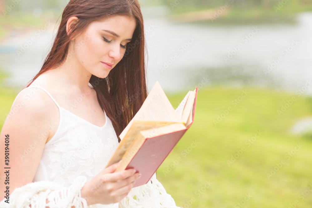 Obraz premium Girl in a rainy park reading a book