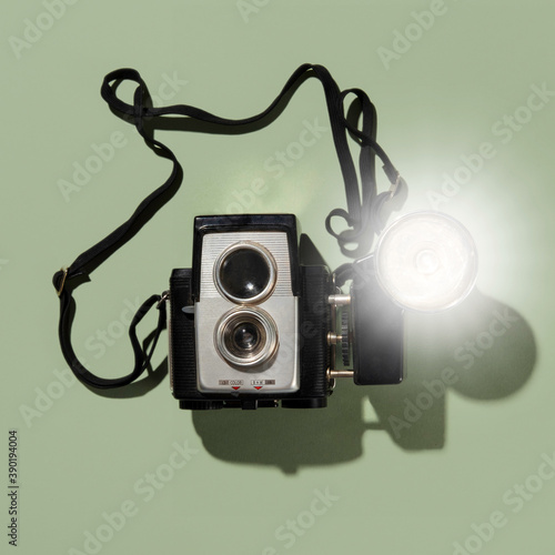 Retro camera with blub flash on green background photo