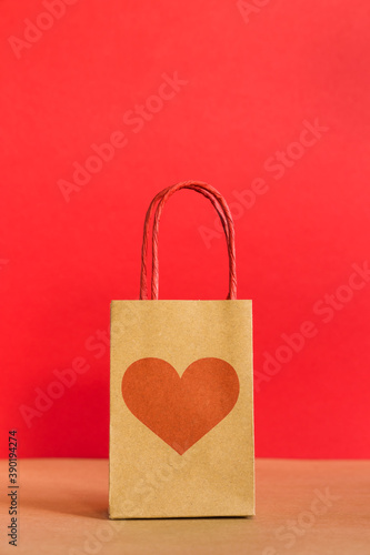 Valentine's Day concept. Shopping paper bag with heart print on red background. 