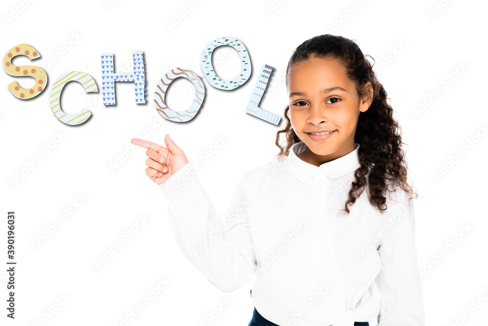african american schoolgirl pointing with finger at school lettering while looking at camera isolated on white african american schoolgirl pointing with finger at school lettering while looking at camera isolated on white