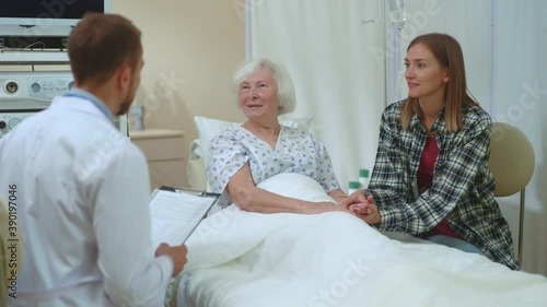 In hospital room old female patient with daughter being told disappointing diagnosis. Young caucasian doctor telling treatment medication to elderly woman.
