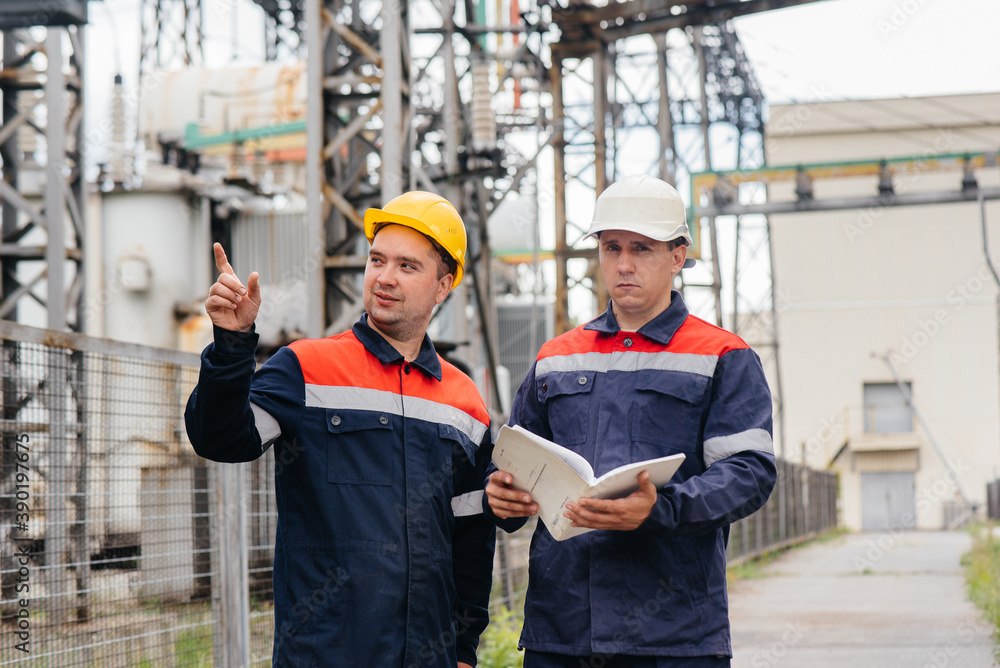 Two specialist electrical substation engineers inspect modern high-voltage equipment. Energy. Industry Two specialist electrical substation engineers inspect modern high-voltage equipment. Energy. Industry