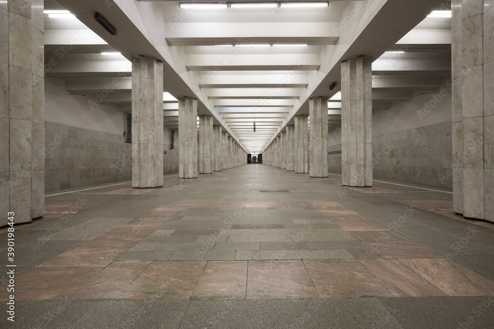 Linear perspective symmetrical view of an underground station with two rows of multiple columns. No people