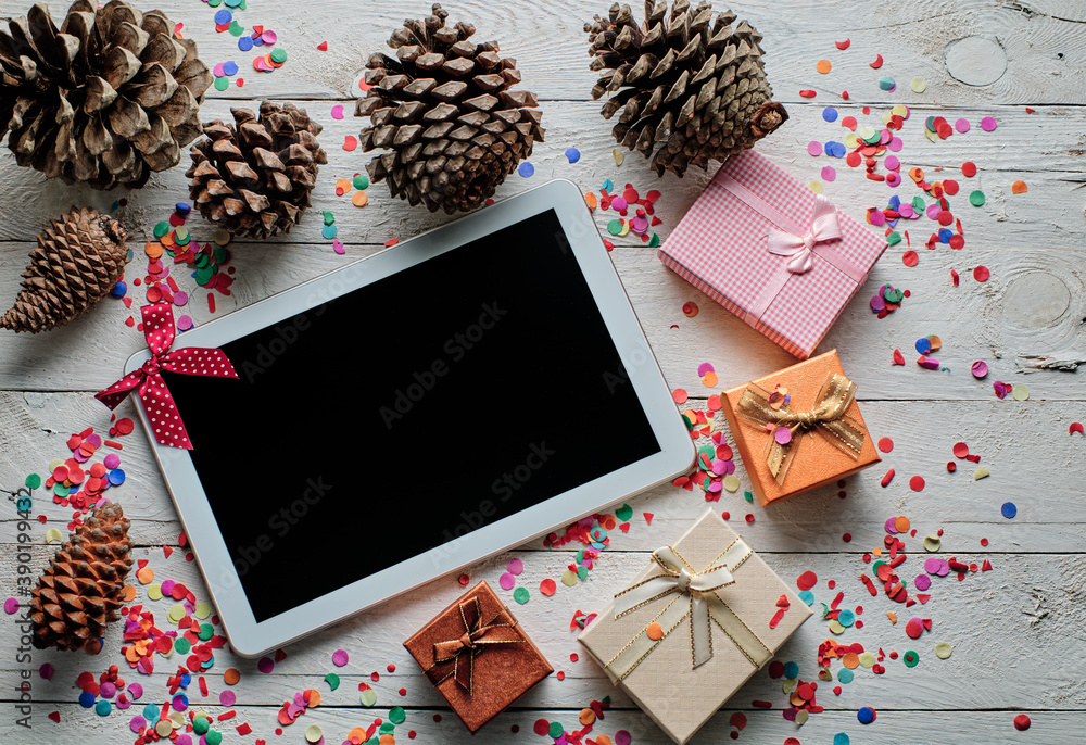 Christmas online shopping background. Tablet screen with wooden copy space top view and gifts.