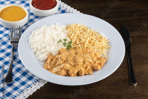 Food dish with chicken stroganoff and rice and chips.