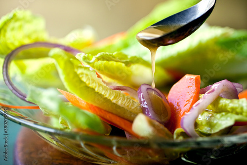 Close up of mustard vinaigrette pouring over salad served on plate photo