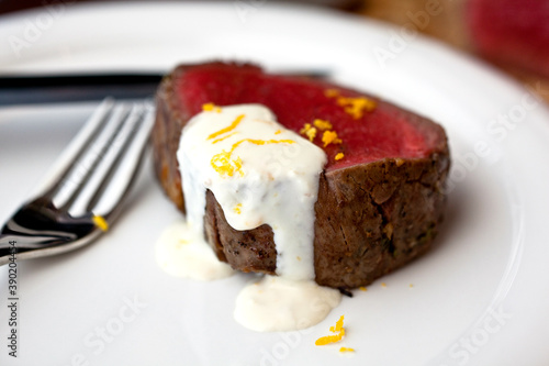 Close up of garlicky roasted beef tenderloin with orange horseradish sauce served on plate