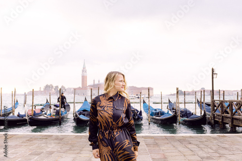 Blonde woman in Riva degli Schiavoni, Venice, with gondolas in the background
 photo