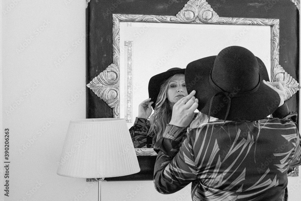 Photo in black and white, woman in a hotel looking at herself in the mirror