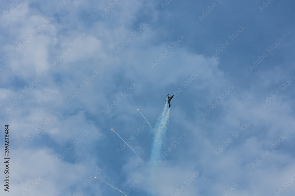 Fototapeta premium fighter plane flies up steeply at a air show with blue sky and clouds