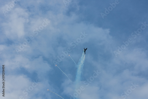 fighter plane flies up steeply at a air show with blue sky and clouds © thomaseder