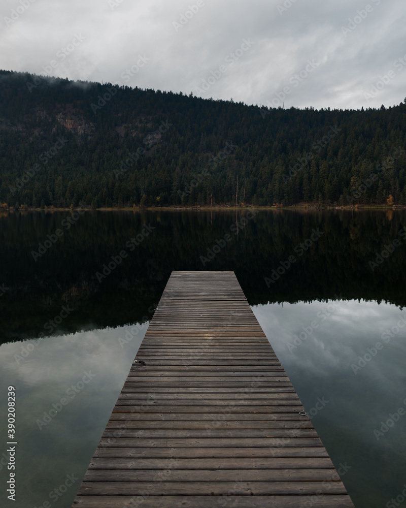 A dock on a peaceful lake on an overcast evening A dock on a peaceful lake on an overcast evening