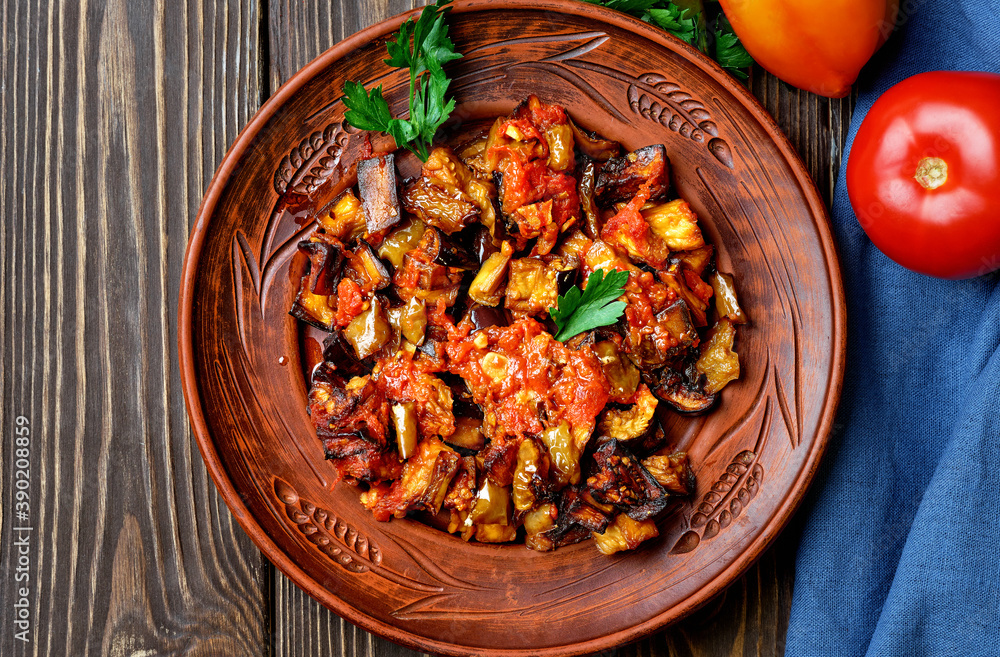Grilled Turkish eggplants in tomato sauce (soslu patlican or saksuka.). A tasty and simple Turkish dish or appetizer for main courses. Layout on dark wooden Grilled Turkish eggplants in tomato sauce (soslu patlican or saksuka.). A tasty and simple Turkish dish or appetizer for main courses. Layout on dark wooden