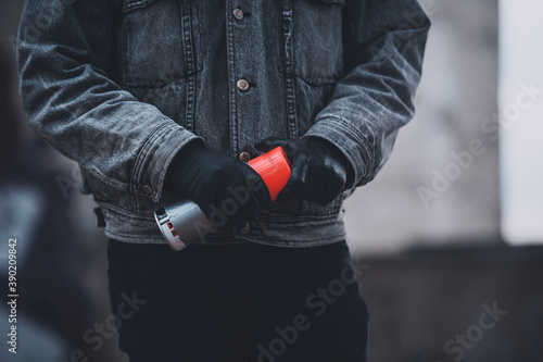 Man in gloves and denim jacket takes a spray paint. Gray days of graffiti artist © Nik Viatkin