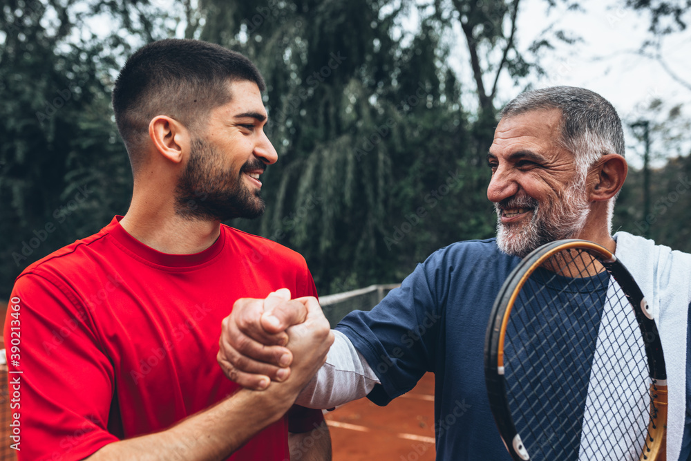 senior man playing tennis with his son senior man playing tennis with his son