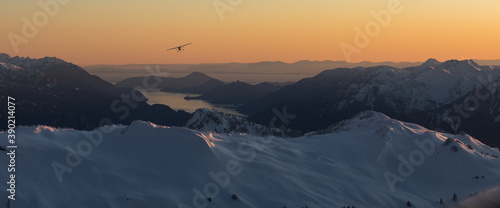 A single engine airplane flying through snowy mountains at sunset
