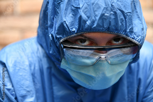 Tired doctor  medical worker wearing a protective suit  goggles  and a surgical mask. Health care staff  nurse  high-quality medical care  coronavirus concept.