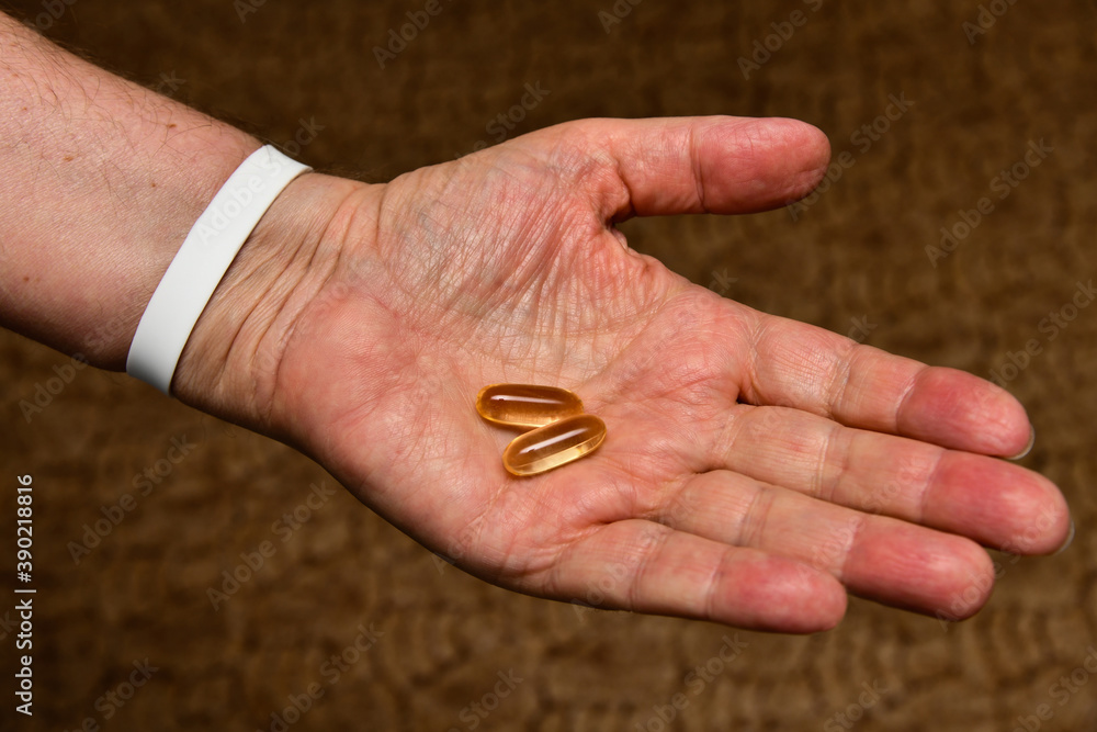 An elderly man holds vitamin D and fish oil, Omega capsules in his hands An elderly man holds vitamin D and fish oil, Omega capsules in his hands