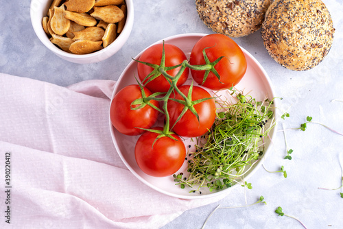 microgreens with tomatoes on a white plate and white plate with cookies and cereal buns