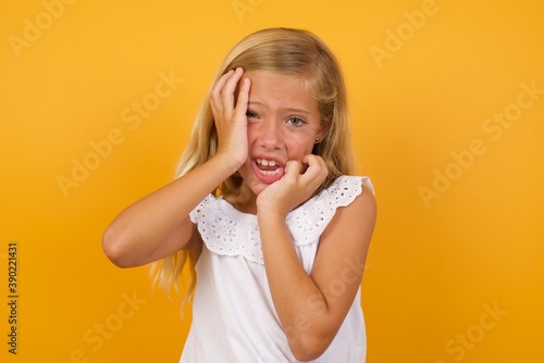 Young gloomy Beautiful Caucasian young girl standing against yellow background, hiding face with hands pouting and crying, standing upset and depressed complaining about job problem.