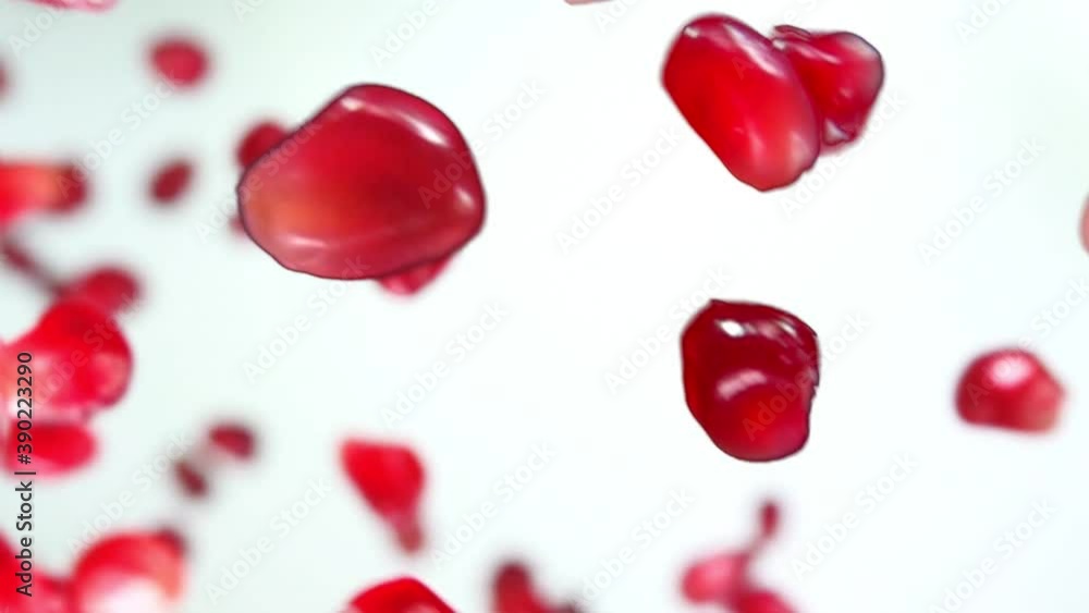 Red fresh juicy grains of ripe pomegranate are bouncing on the white background in slow motion Red fresh juicy grains of ripe pomegranate are bouncing on the white background in slow motion