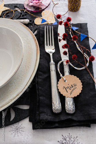 Christmas silverware on a black elegant napkin next to two dishes. The name Mike is on a round tag.