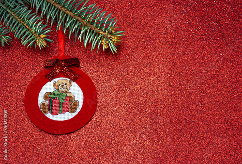 Handmade red Christmas tree toy made of felt in the form of a ball with a cross-stitch teddy bear