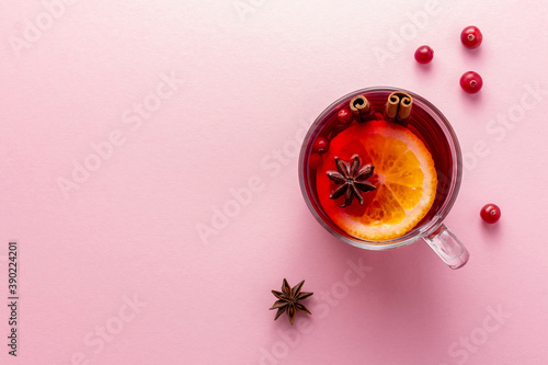 A glass cup of christmas mulled wine or glogg on pink background with copy space photo
