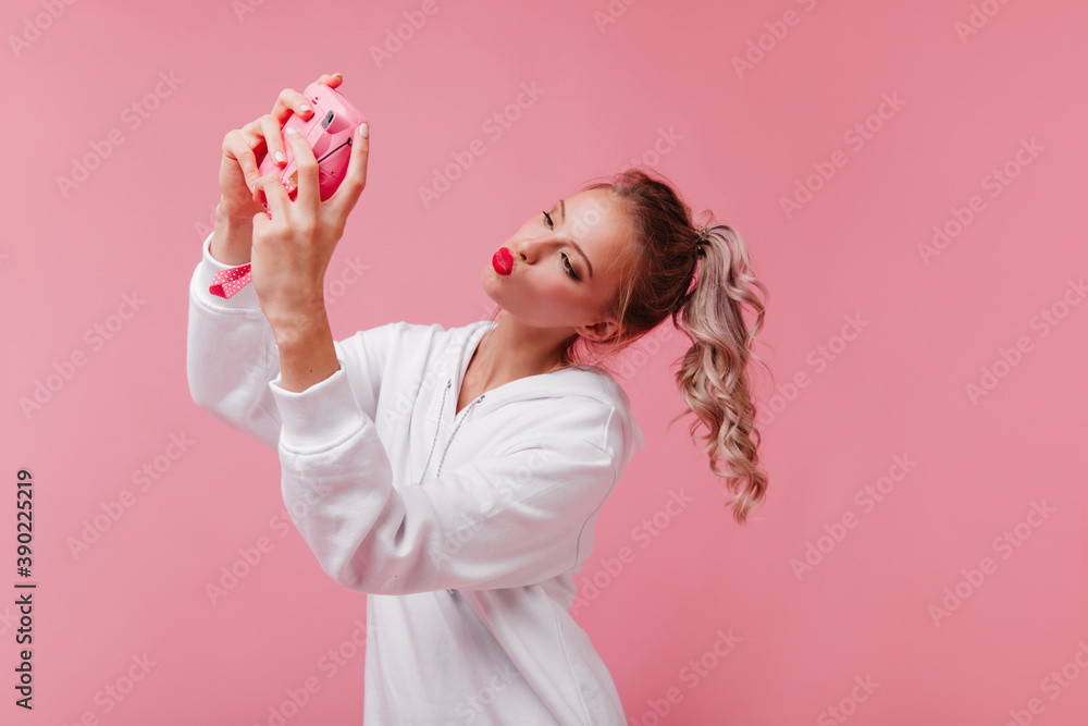 Adorable girl with curly hair posing with kissing face expression. Graceful european lady working with camera in studio Adorable girl with curly hair posing with kissing face expression. Graceful european lady working with camera in studio