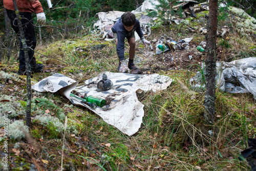 big amount of trash in forest, family father and son picking garbage away, global environment issues