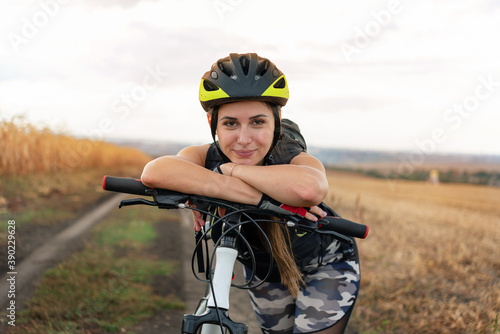 sporty girl standing in the middle of the field leaning on a bicycle